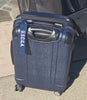 Blue suitcase with 'U.S.C.G.A.' label on a sidewalk