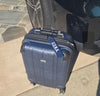Blue suitcase with 'U.S. Navy' branding attached to a vehicle on a sidewalk.